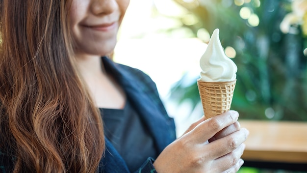 Premium Photo | Closeup image of a woman holding and eating soft serve ...