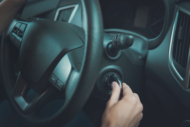 イグニッションでキーを保持している女性の手の車内のクローズアップ 車の回転キーのエンジンを始動する女性 ハンドルと女性の自動車 の始動 女の子が目的地に来て車を止めます プレミアム写真