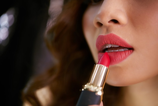Closeup of lipstick touching plump red female lips Free Photo
