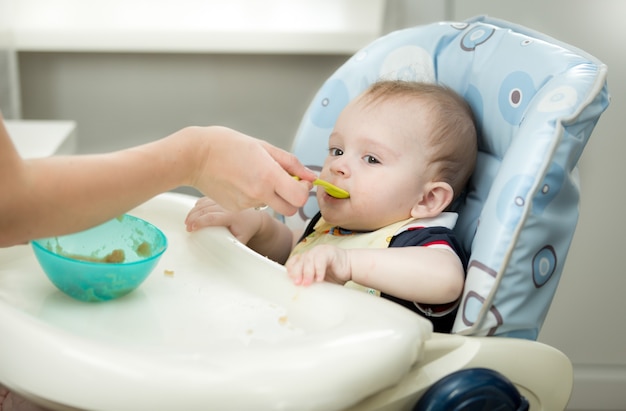 Premium Photo | Closeup of mother giving porridge from spoon to her baby