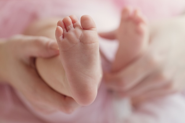 Closeup Of Mother Hands Holding Cute Tiny Baby Feet Showing Baby