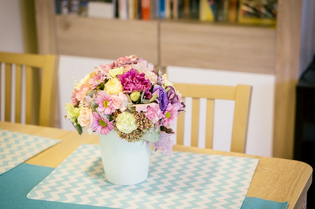 木製のテーブルの上の白い花瓶に色とりどりの花の花束のクローズアップ 無料の写真