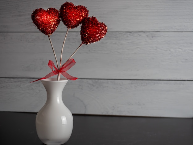 灰色の背景に花瓶の赤いハート型の装飾的なポップのクローズアップ 無料の写真