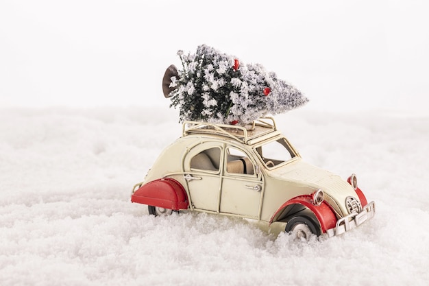 人工雪の屋根にクリスマスツリーと小さなヴィンテージのおもちゃの車のクローズアップ 無料の写真