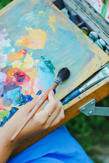 Premium Photo | Closeup of paintbrush in woman hands mixing paints on ...