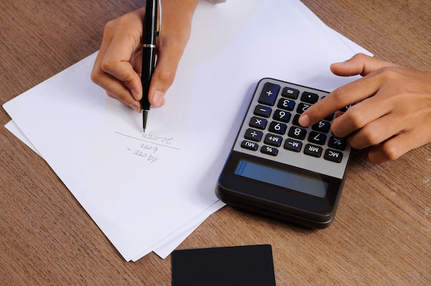 free-photo-closeup-of-person-calculating-on-calculator-and-writing