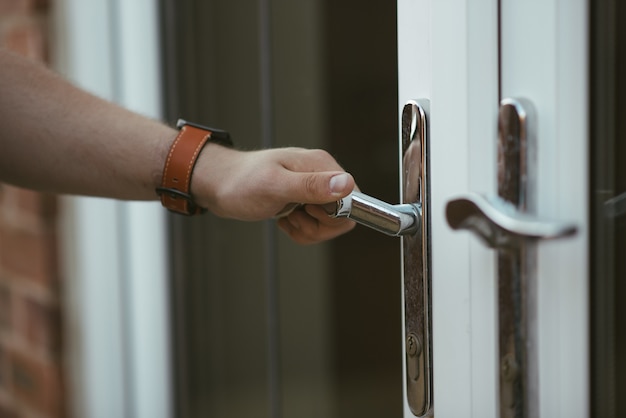 Closeup shot of a person holding a door knob and opening the door Free Photo