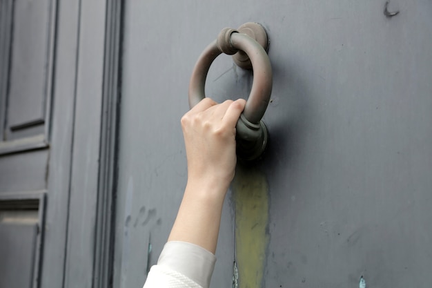 Closeup shot of a person knocking on the door with an old door knocker Free Photo