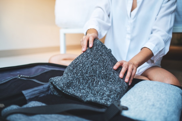 Premium Photo | Closeup of a woman folding clothes and packing luggage ...