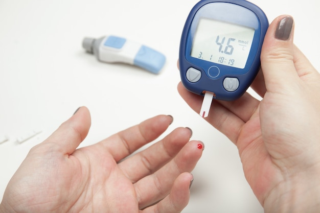 Closeup of woman hands testing high blood sugar with glucometer Premium Photo