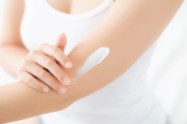 Closeup young asian woman applying sunscreen cream lotion on skin Premium Photo