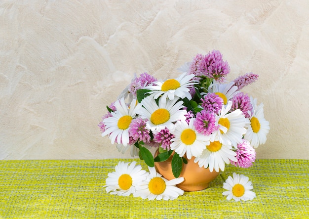 明るい背景の花瓶にクローバーとカモミールの花束 庭と野の花の夏の花束 ヒナギクのある静物 プレミアム写真