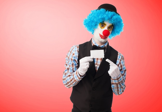 Free Photo | Clown holding and pointing a white card