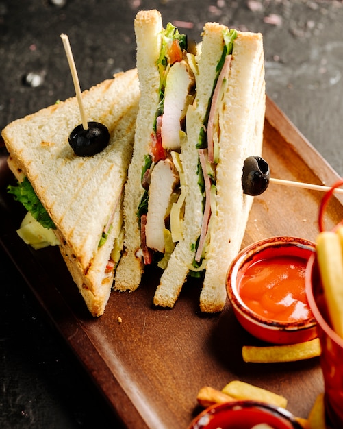 Club sandwiches with hot chili sauce and french fries. Free Photo