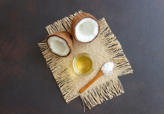 Premium Photo | Coconut oil in a jar and fresh coconuts on a dark ...