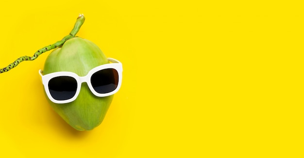 Premium Photo | Coconut with sunglasses on yellow background.