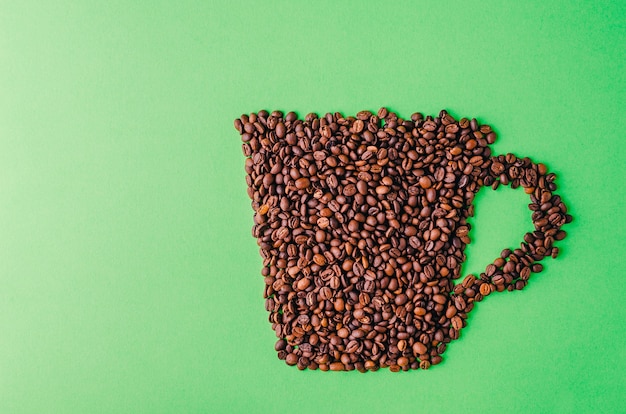 緑の背景にコーヒー豆で作られたコーヒーカップ クールな壁紙に最適 無料の写真