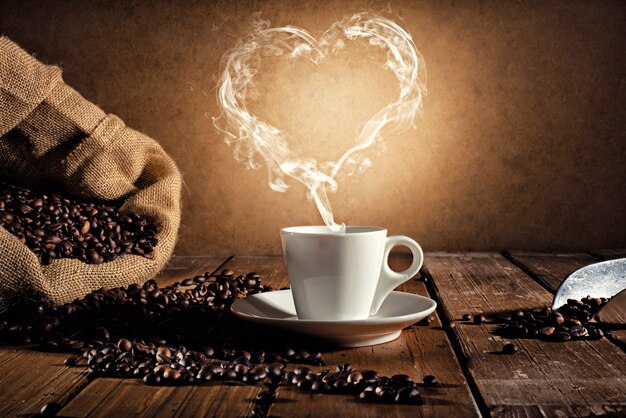 Premium Photo | Coffee cup over a wooden table with a smoke shaped as ...