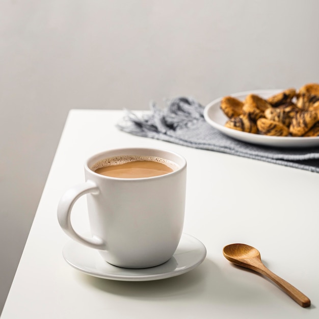 Free Photo | Coffee mug on table with cookies on plate and spoon