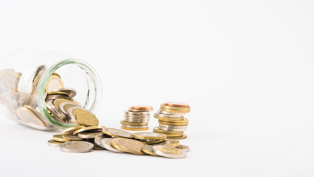 Coins scattered from glass jar Free Photo