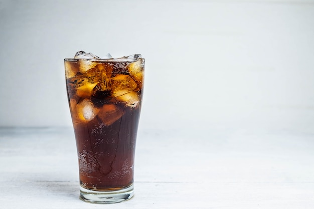 Cola soda in a glass on a white table Premium Photo