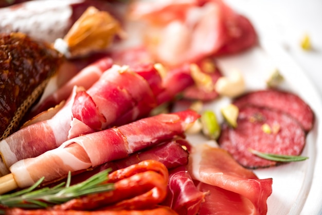 Cold smoked meat plate. traditional italian antipasto, cutting board with salami, prosciutto, ham, pork chops, olives on grey background. top view, copy space, flat lay Premium Photo