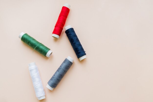 Premium Photo | Collection of various sewing threads on pastel background.