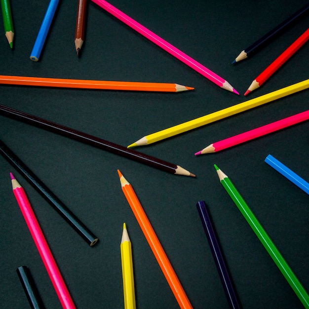 Premium Photo | Color pencils scattered throughout the frame on a black ...