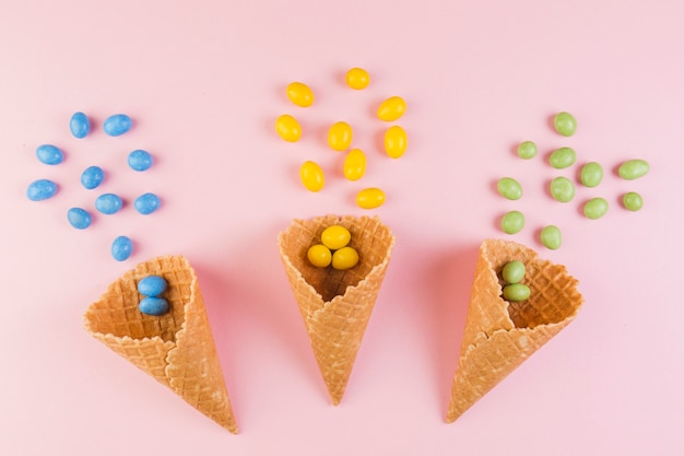 colorful-candies-spilling-from-ice-cream-waffle-cone-pink-background_23-2147921669.jpg