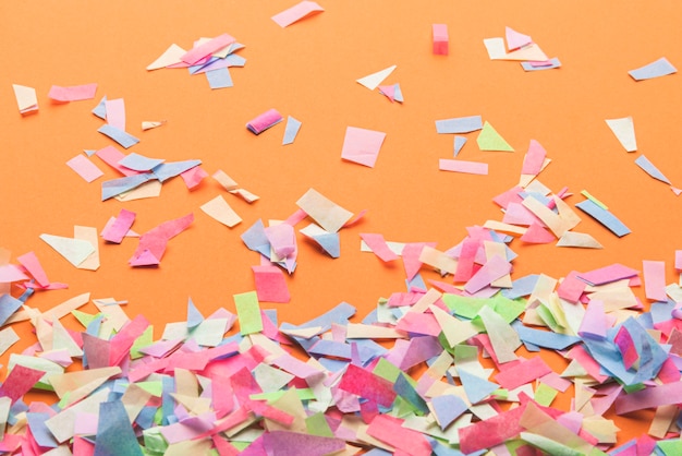 Colorful confetti on orange background | Free Photo