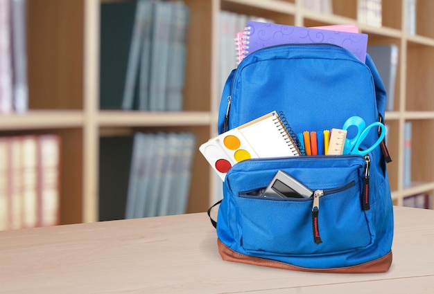 Premium Photo | Colorful school supplies in backpack on classroom ...