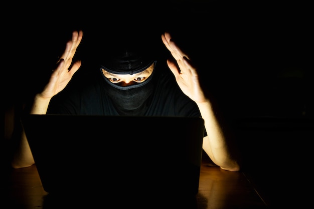 Computer hacker doing his job with laptop computer in the dark room Free Photo