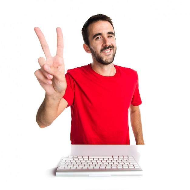 Computer technician working with his keyboard making victory gesture Premium Photo