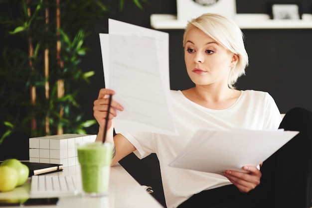 Concentrated businesswoman comparing documents at office Free Photo