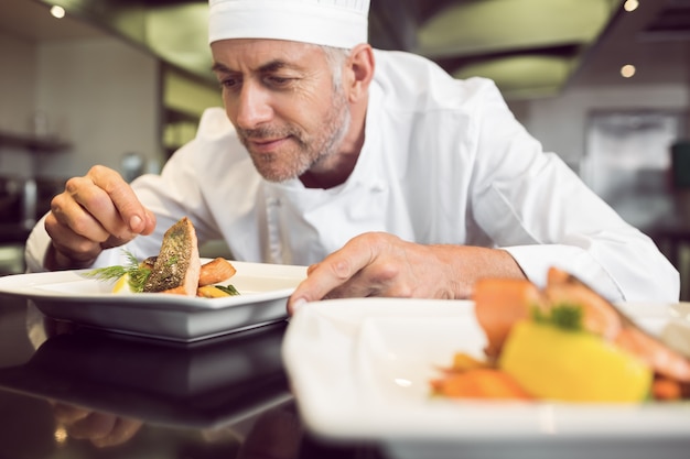 Premium Photo | Concentrated male chef garnishing food in kitchen