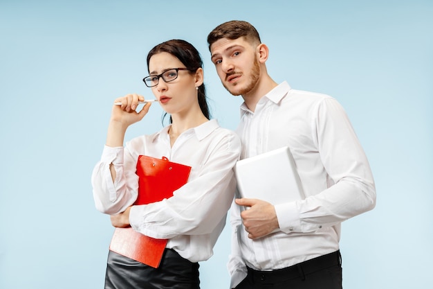 Concept of partnership in business. young emotional man and woman against blue background at studio. human emotions and partnership concept Free Photo