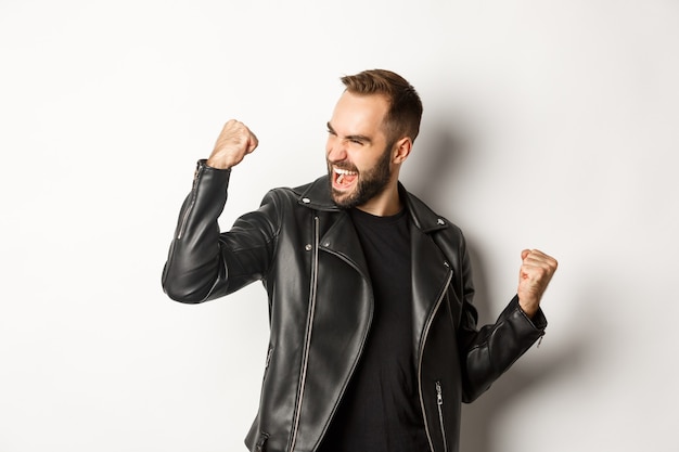 Free Photo | Confident Bearded Man Celebrating Victory, Winning Prize, Making Fist Pump And Rejoicing, Wearing Black Leather Jacket
