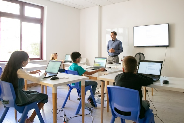 Confident teacher explaining lesson to pupils Free Photo