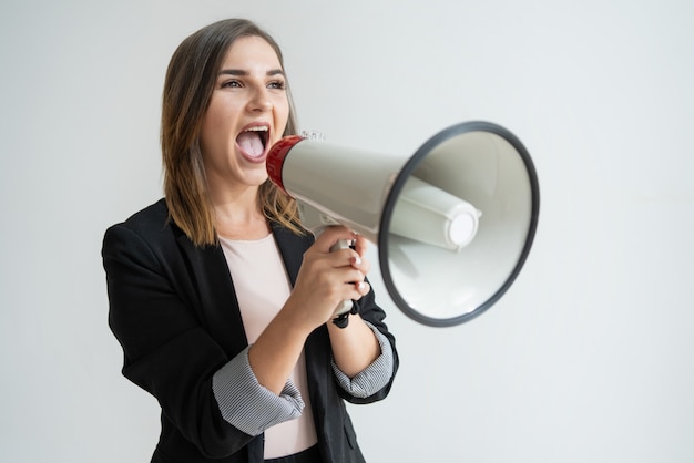 Confident young caucasian woman shouting aside in megaphone Free Photo