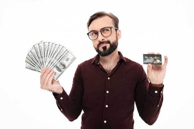 Free Photo | Confused thinking young man holding money and credit card.