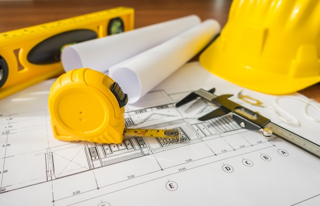 Construction plans with yellow helmet and drawing tools on bluep Free Photo