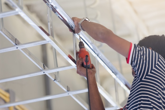  Construction  worker ceiling  metal frame with screwdriver 