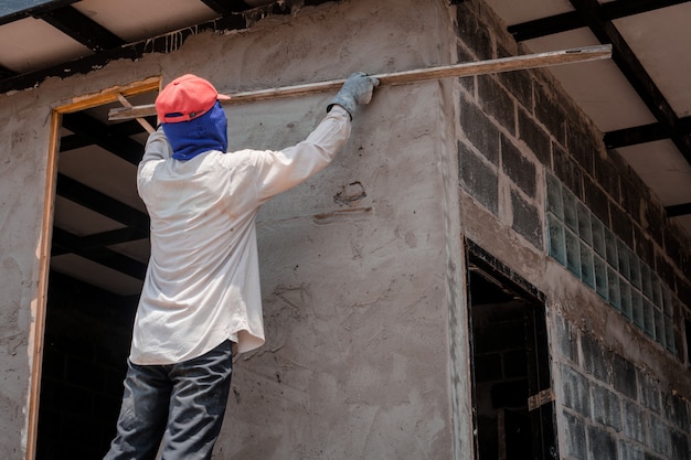 Construction Workers Plastering Building Wall Using Cement