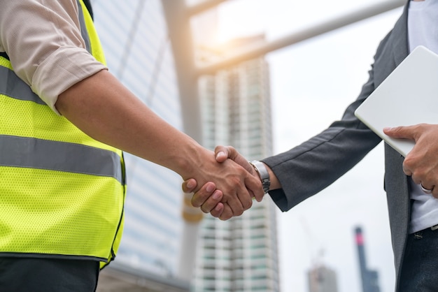 Premium Photo | Construction workers in protective helmets and vests are shaking  hands while working