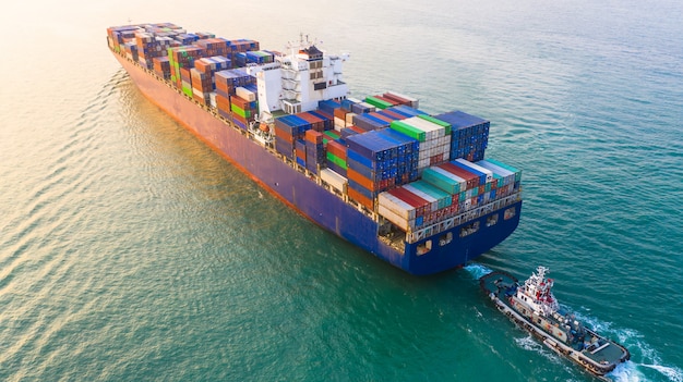 Container ship arriving in port, container ship and tug boat going to sea port, logistic business import export shipping and transportation, aerial view. Premium Photo