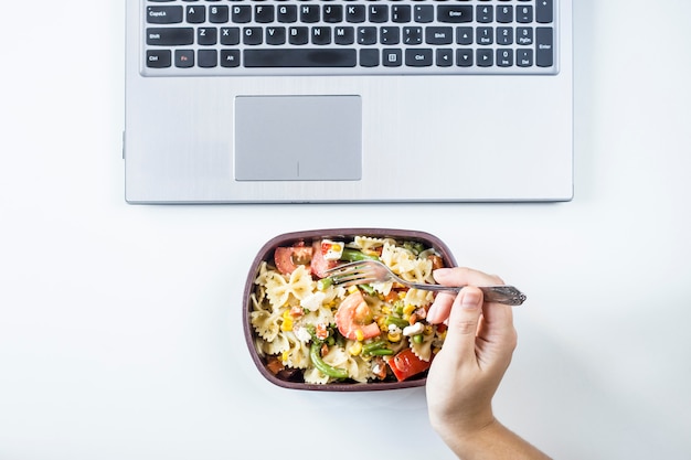Premium Photo | Container with salad with pasta in the workplace near ...