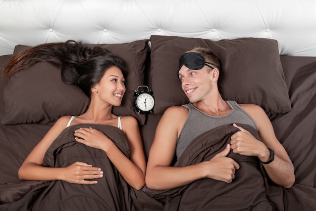 Premium Photo A Contented Young Couple Is Lying In Bed An Alarm