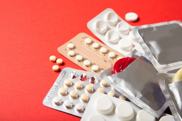 Premium Photo Contraceptive Pills And Condoms On A Red Background