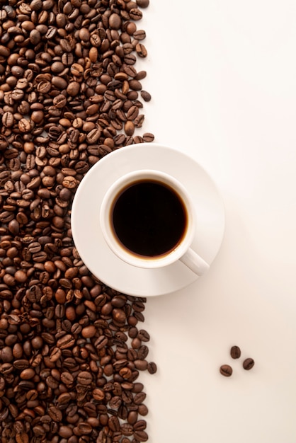無料の写真 対照的なコーヒー豆の背景とカップ