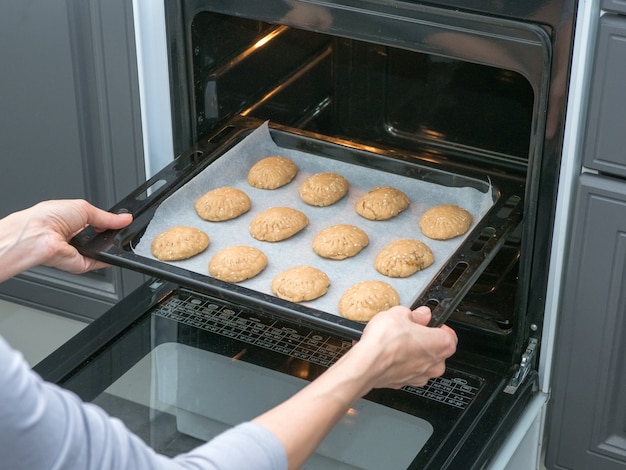 Premium Photo | The cook bakes cookies in the oven in the kitchen ...